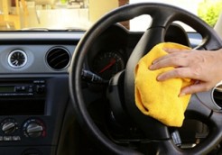 Woman's nand with microfiber cloth polishing steering wheel of an SUV car